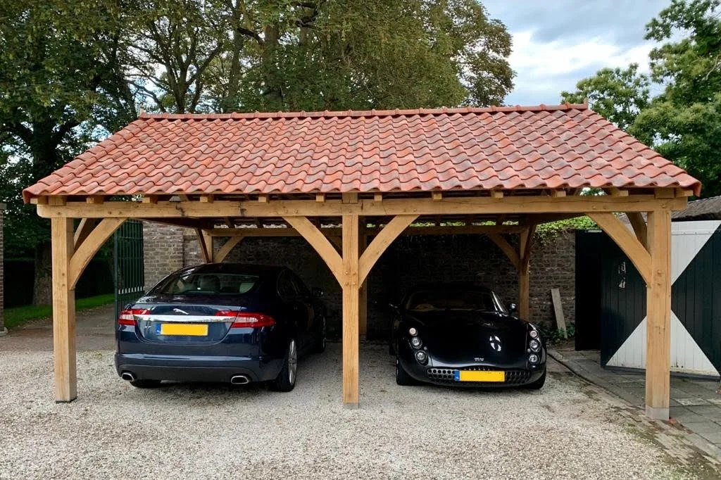 Afgebouwde eiken carport met rode dakpannen, met een Jaguar en een TVR onder de overkapping