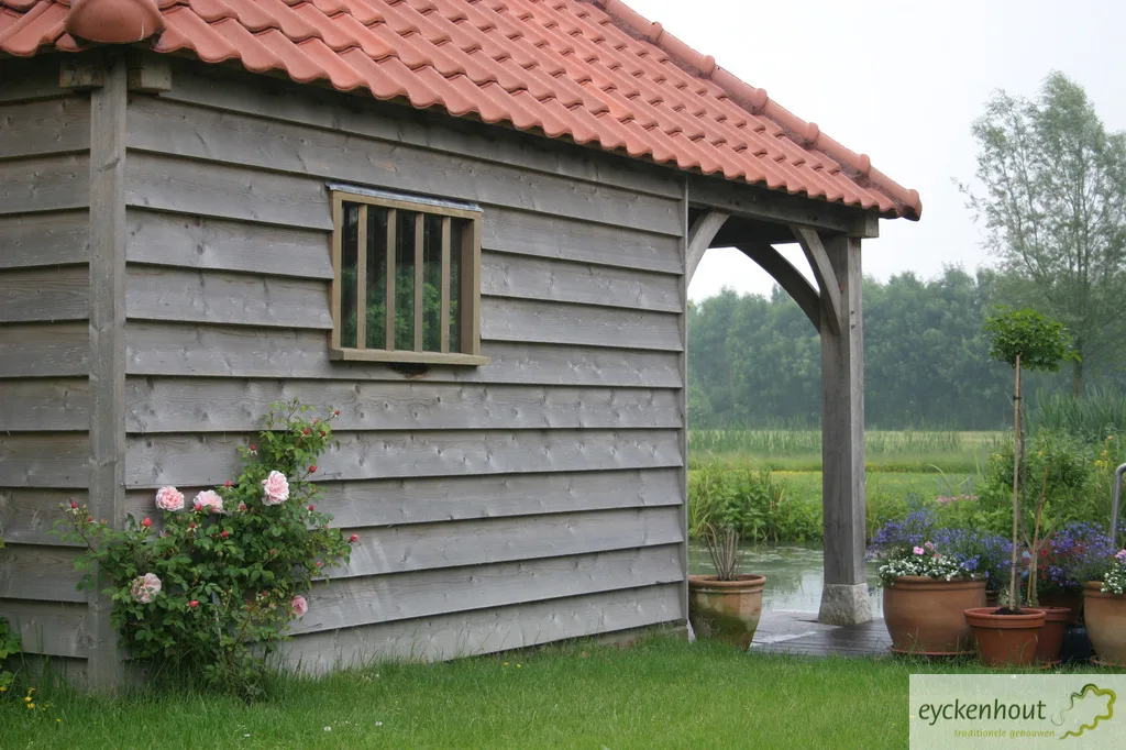 Eiken bijgebouw met terras bij een zwemvijver