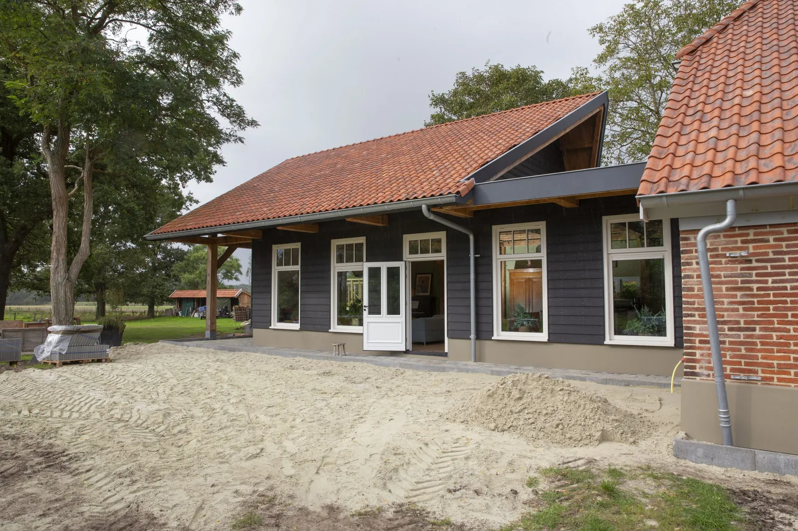 De aanbouw naast het bestaande woonhuis, tijdens de afronding van het terrein