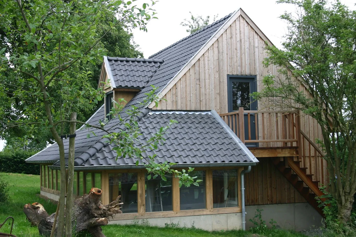 Het gebouw in vol zicht, met beglaasde onderbouw en eiken buitentrap