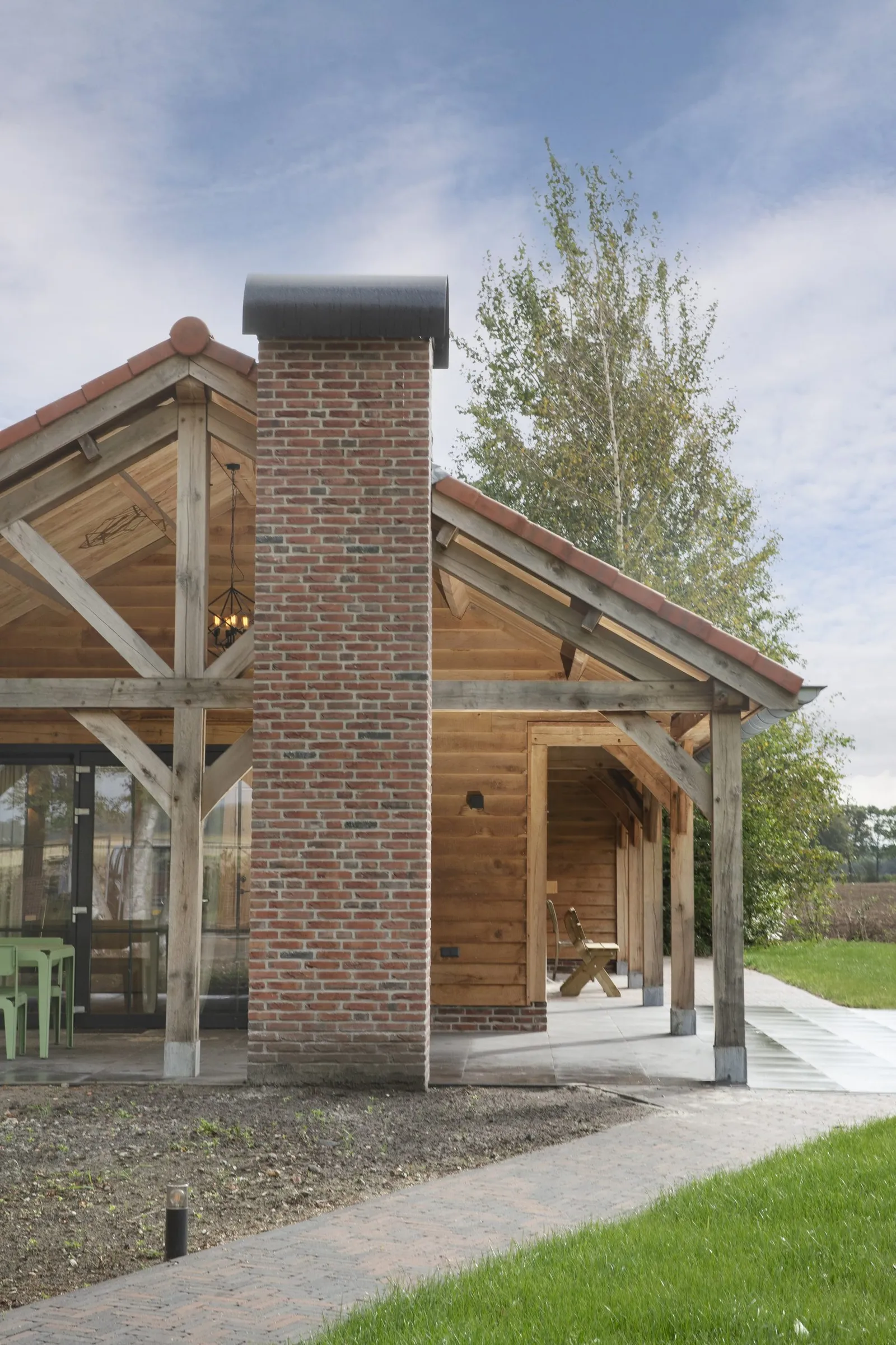 Gemetselde schoorsteen tussen twee overkappingen van de recreatiewoning