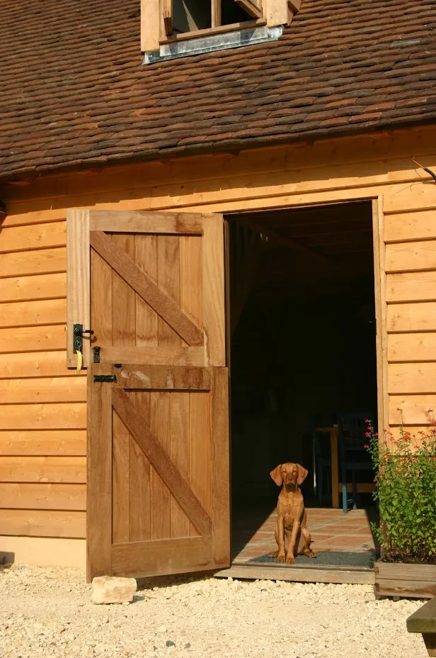 Openstaande eiken deur met de hond in de deuropening