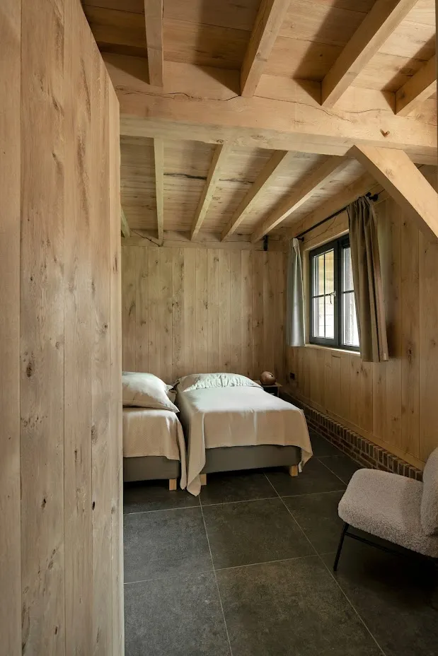 Slaapkamer met eiken balkenplafond onder de kap
