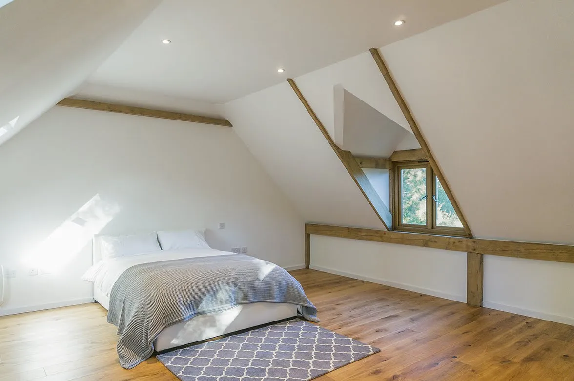 Slaapkamer onder de kap, met eiken balken en een dakkapel