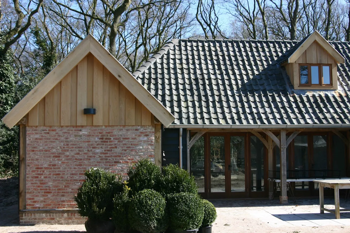 Topgevel in baksteen en eiken, met buxus in potten voor de veranda