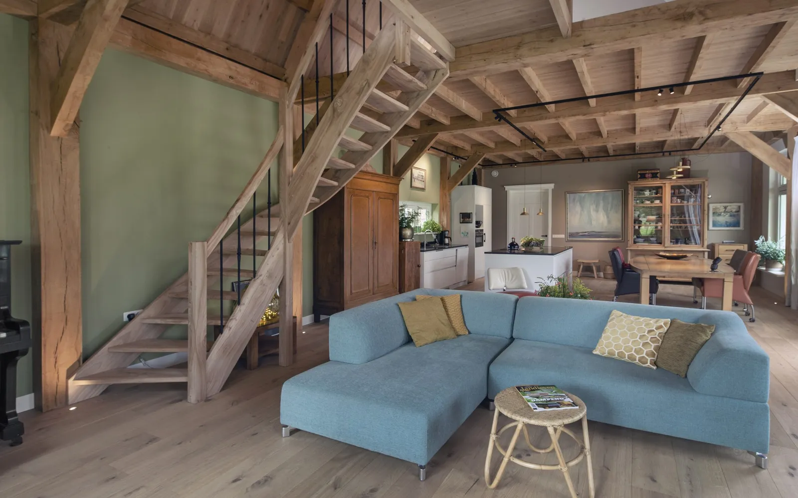 Woonkamer met eiken trap en gebint, en een blauwe hoekbank