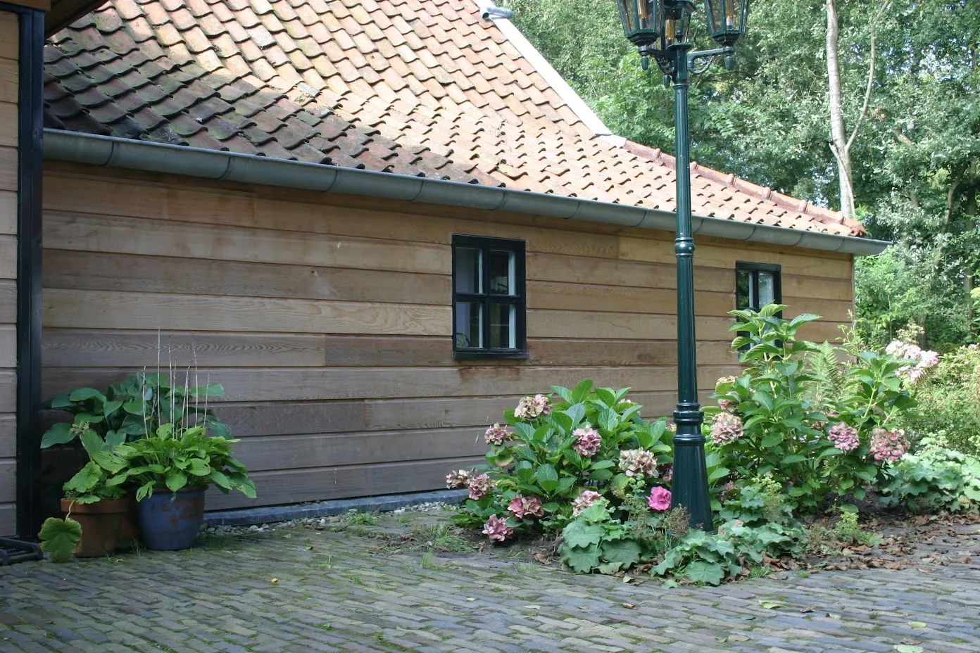 Zijgevel in eiken potdekselwerk, met oude pannen en hortensia's
