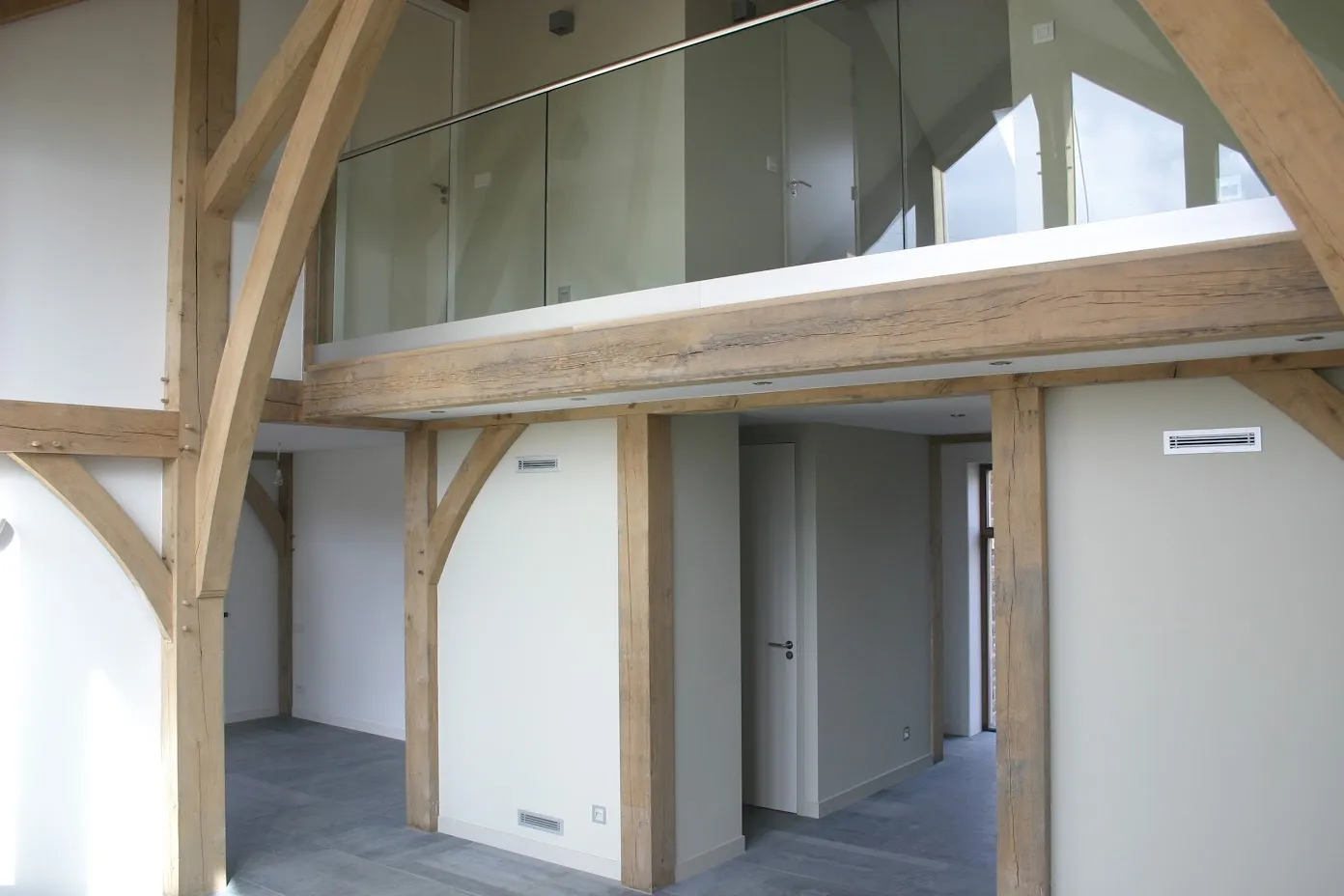 Vide met glazen balustrade tussen de eiken gebinten
