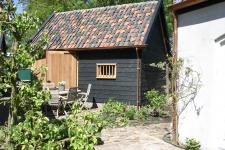 eiken schuur met zwart potdekselwerk en oude holle pannen, het bijgebouw ook voorzien van koperen goten.